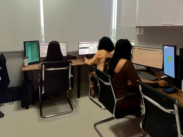 Colaboradoras do escritório atendendo clientes em outra sala da equipe