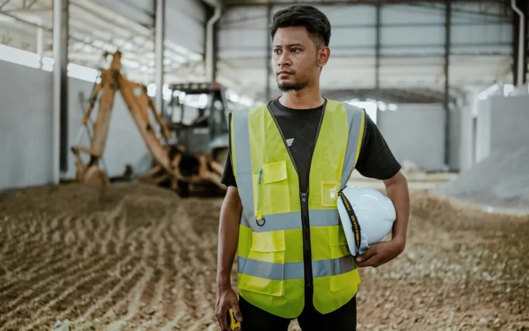 Trabalhador com colete de segurança segurando um capacete
