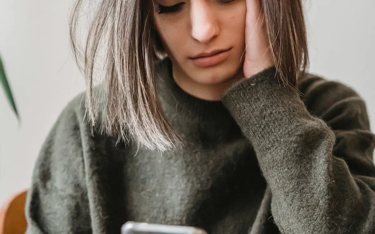 Mulher preocupada olhando para o celular em ambiente doméstico