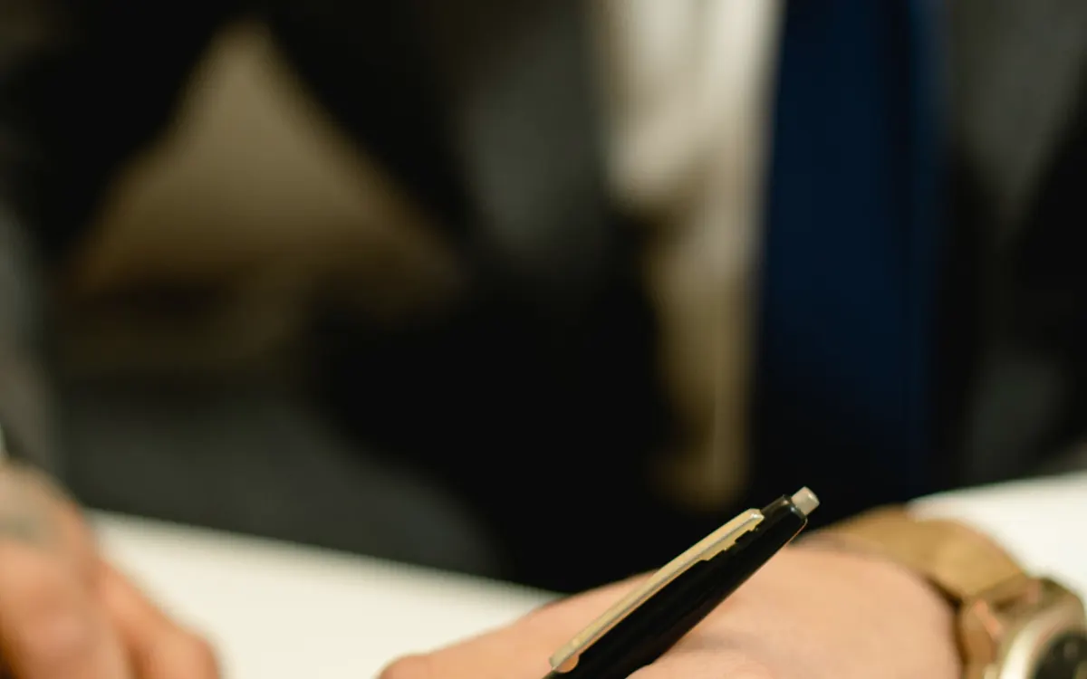 Mão assinando um documento com caneta
