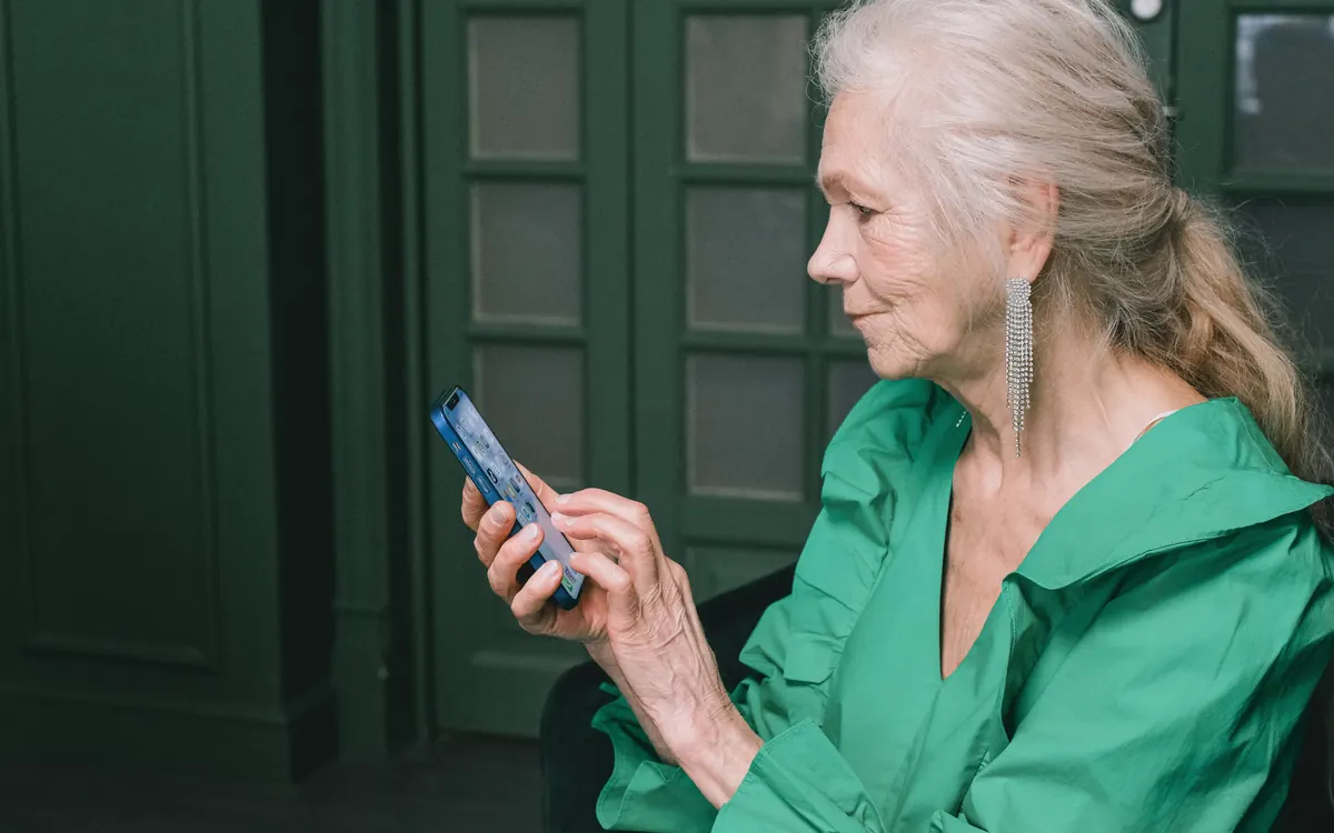 Senhora idosa olhando com atenção a tela do celular em casa